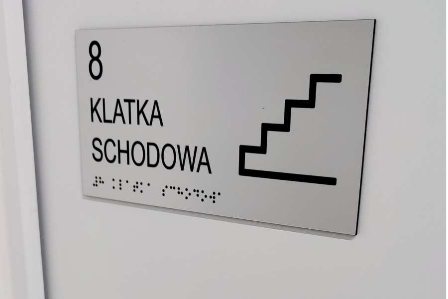 Oznakowanie budynków - tabliczki informacyjne dla osób niepełnosprawnych, klatka schodowa, piktogram i pismo Braille'a